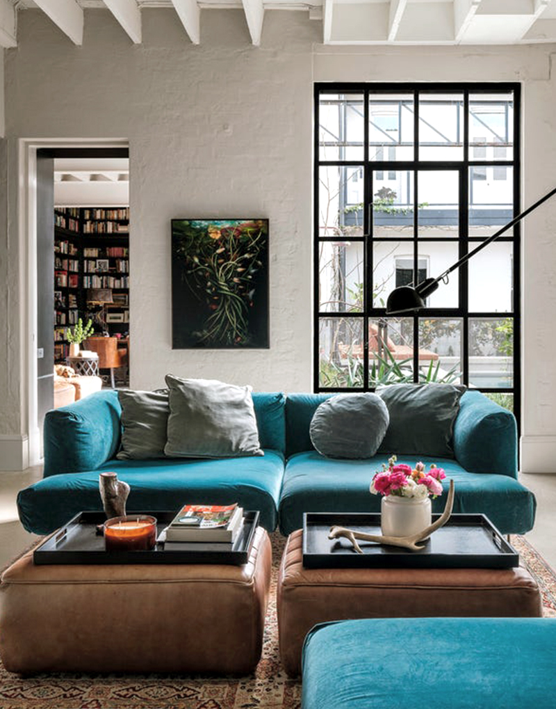 In the living room, you'll find a blue couch paired with a square-shaped leather ottoman.