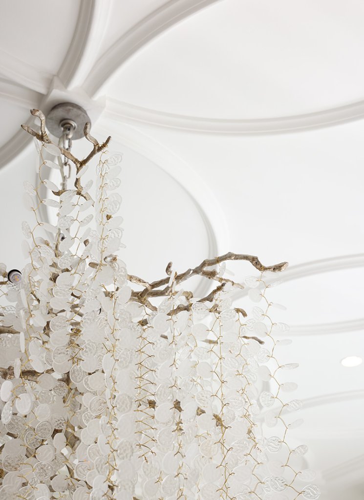 The ceiling roses and boiserie complement each other, Clear and opaque crystal clusters hang below large plaster ‘petals’.